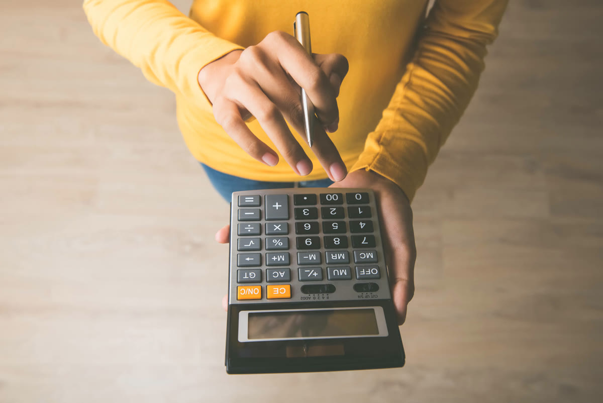 Main utilisant une calculatrice sur une table.