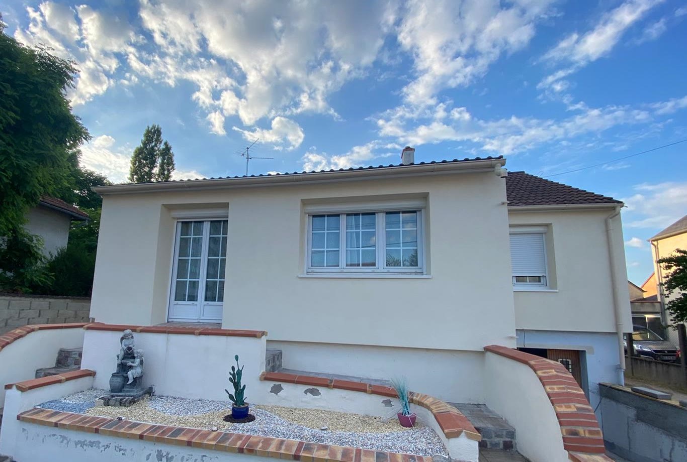 Façade claire d'une maison individuelle vue depuis le jardin.